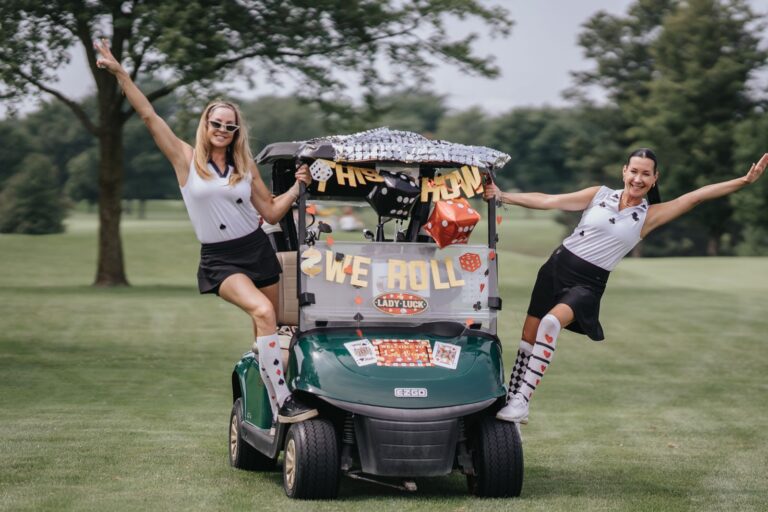 Two golfers leaping beside their decorated cart