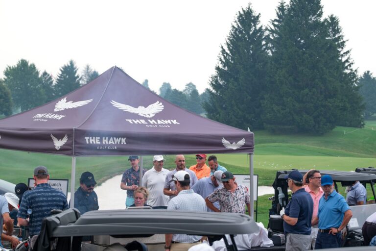Golfers gathering under The Hawk Golf Club tent