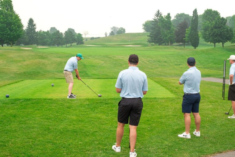 Golfer teeing off as teammates watch